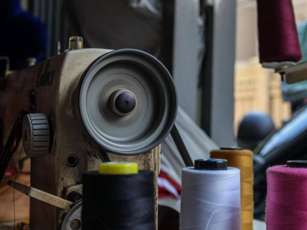Motion blur of a sewing machine wheel with colorful thread spools in a Cambodian workshop.