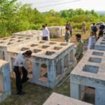 Large, square concrete artificial fish shelter frames being inspected by Cambodian officials and conservation experts in an outdoor field.